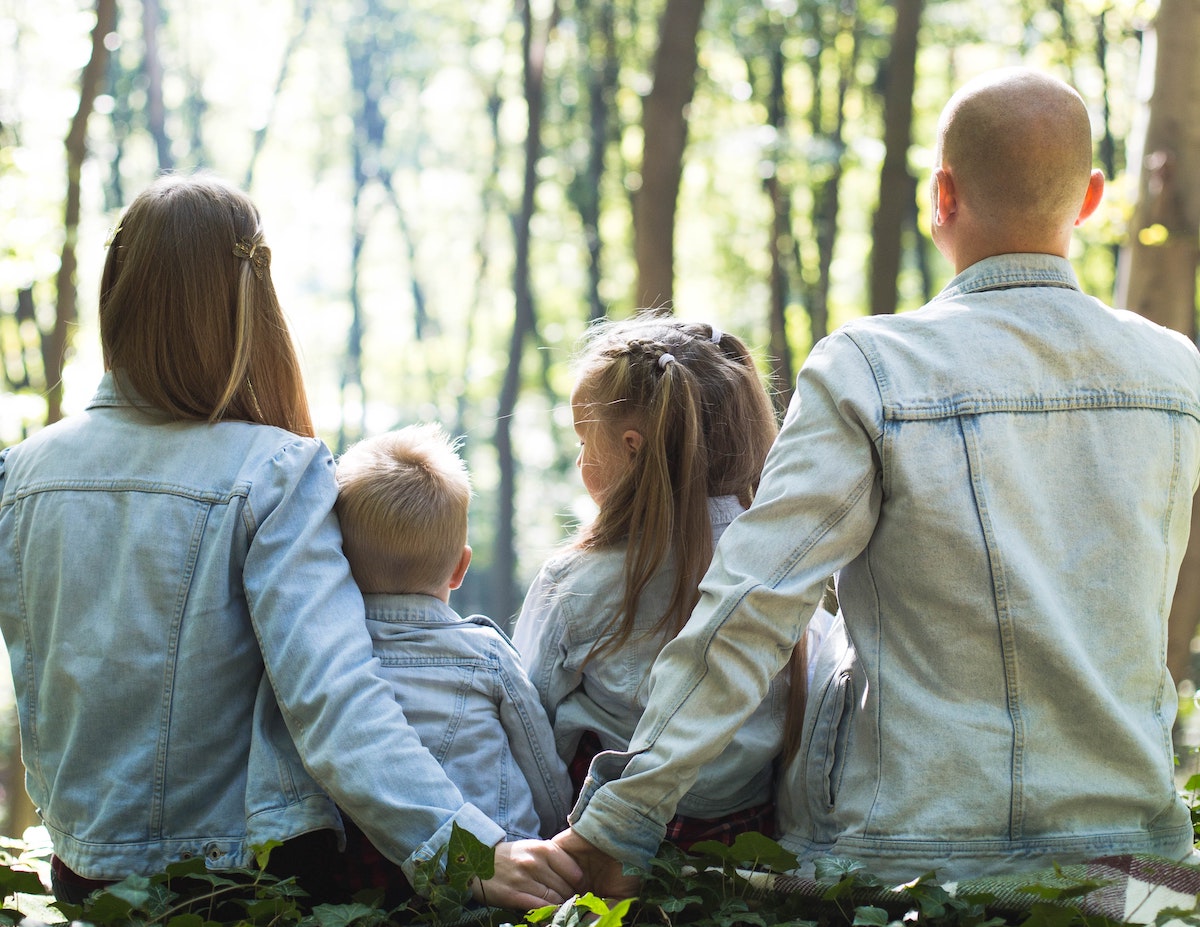 Mann und Frau halten sich hinter den Rücken zweier Kinder an der Hand